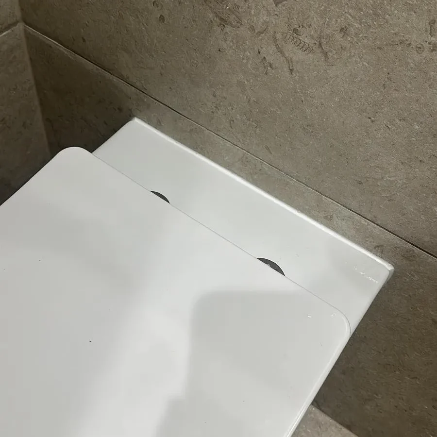 White wall-hung toilet against beige stone-effect wall and floor tiles
